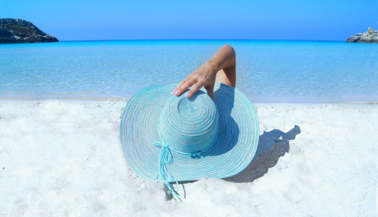 Imagem mostra mulher na praia com chapéu