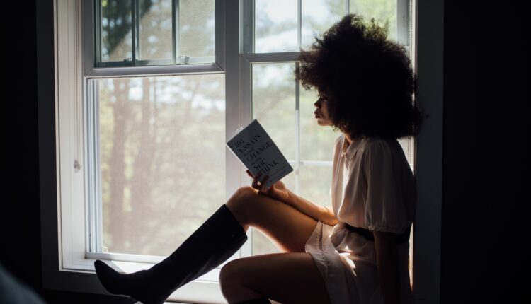 mulher sentada na janela lendo um livro