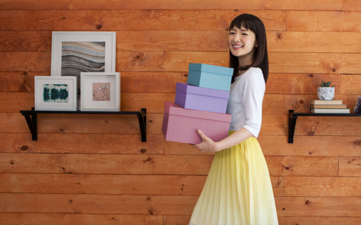 Marie Kondo segurando caixas de arrumação