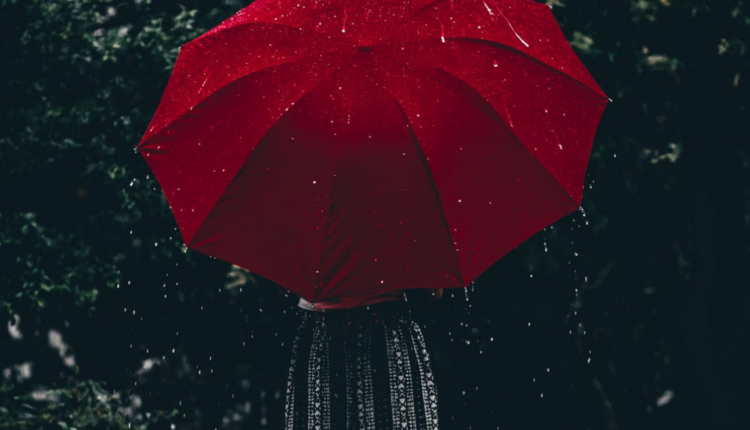 pessoa segurando um guarda-chuvas vermelho