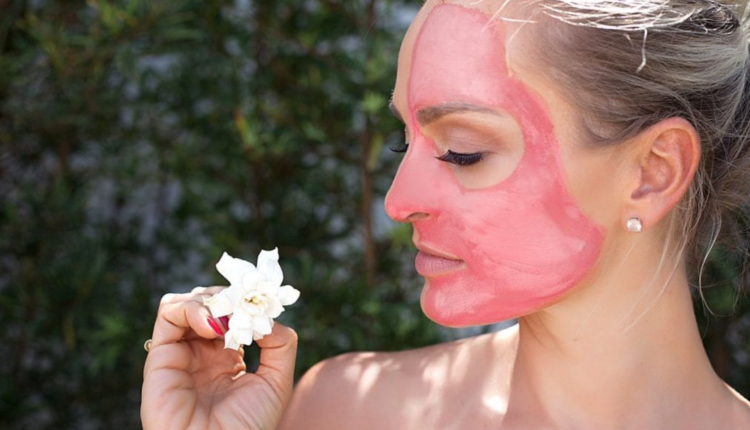 mulher com máscara facial de argila rosa segundo uma flor