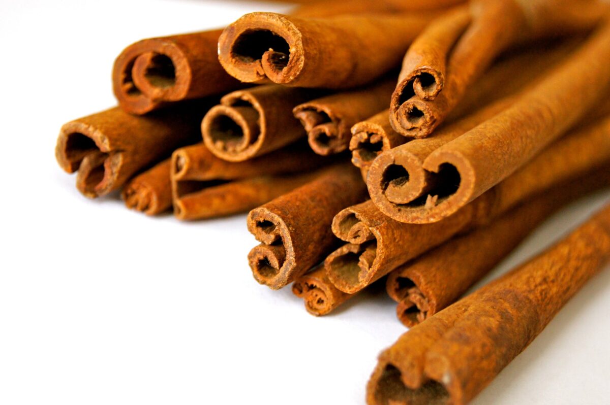 imagem mostra diversos paus de canela em um fundo branco