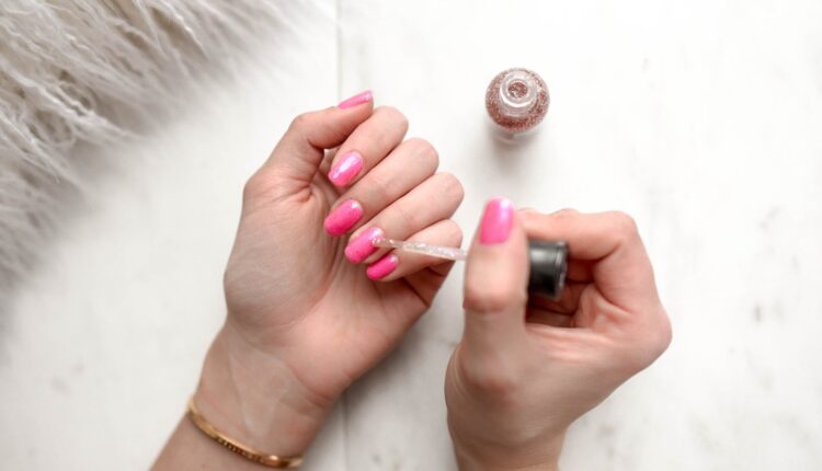 A imagem mostra unhas sendo pintadas de rosa