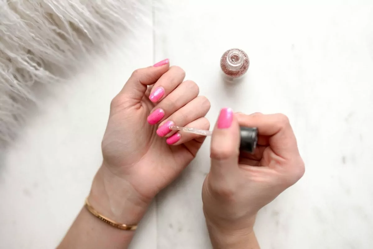 A imagem mostra unhas sendo pintadas de rosa