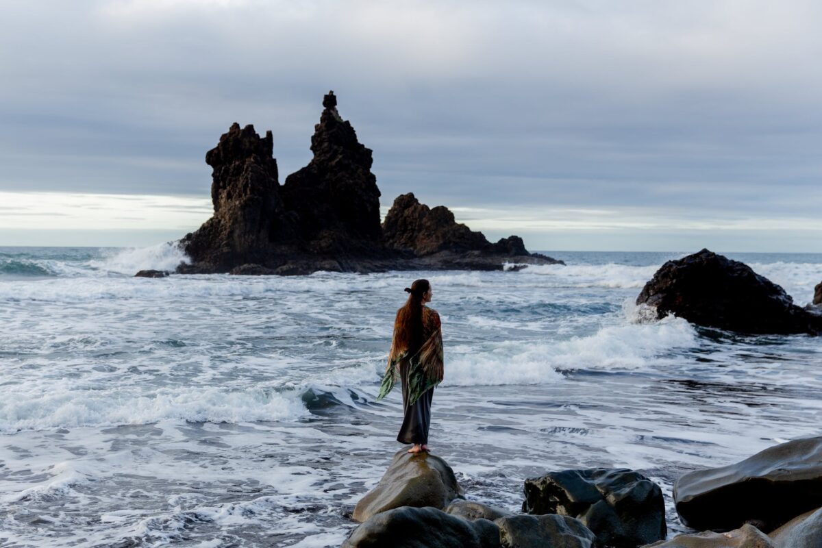 imagem mostra mulher de costas em frente ao mar para ilustrar frases bonitas de Deus