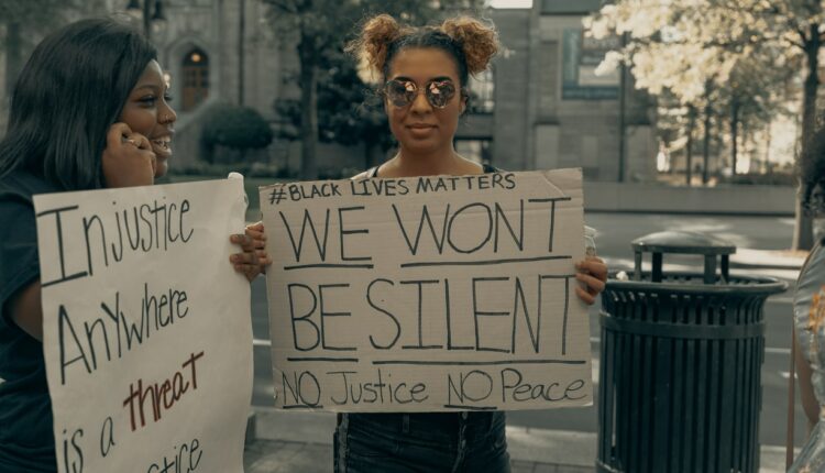 mulher segura cartaz em manifestação com frases contra o racismo