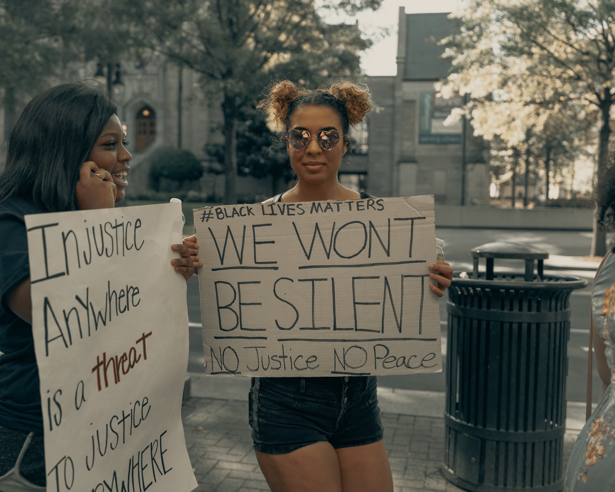 mulher segura cartaz em manifestação com frases contra o racismo