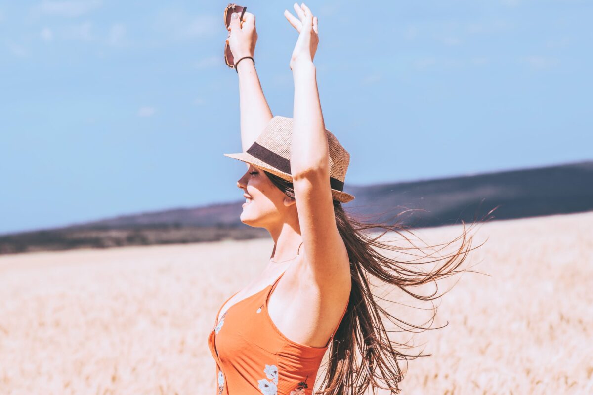 imagem mostra mulher na praia com os braços para cima