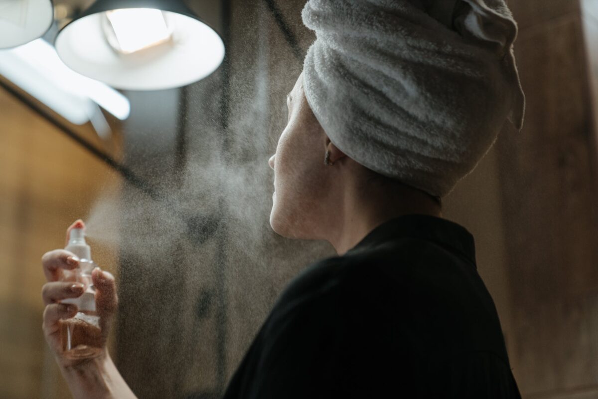 imagem mostra mulher aplicando hidrolato na face
