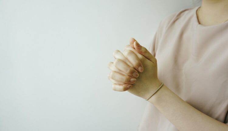 Mãos de uma mulher em prece, rezando