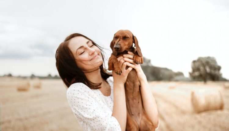 foto mostra uma mulher em um campo segurando um cachorro no colo