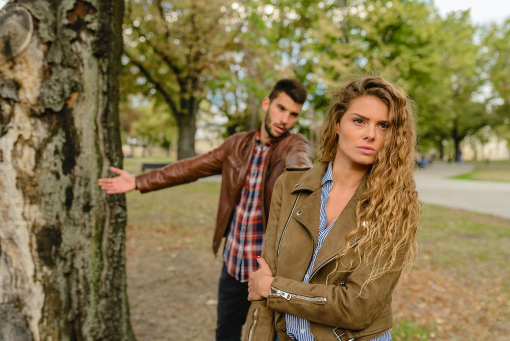 imagem mostra uma mulher de costas para um homem, que tenta conversar com ela, indicando um término