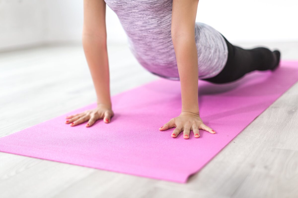 a foto mostra uma mulher praticando yoga com foco no tapete