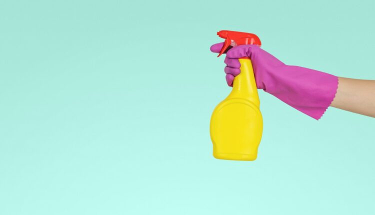imagem mostra mão com luvas segurando spray de limpeza