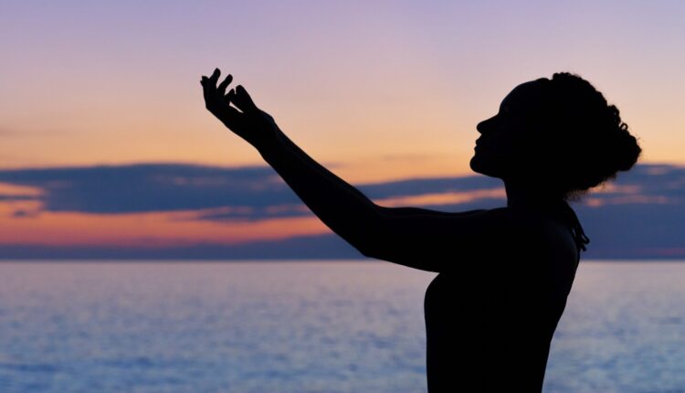 imagem mostra mulher com as mãos em prece para o céu