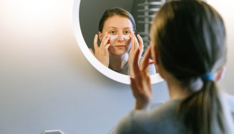 imagem mostra mulher em frente espelho tratando olheiras