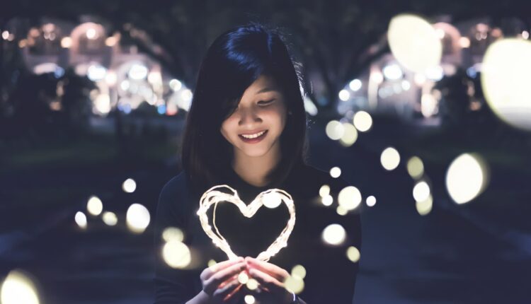 imagem mostra mulher segurando um coração iluminado