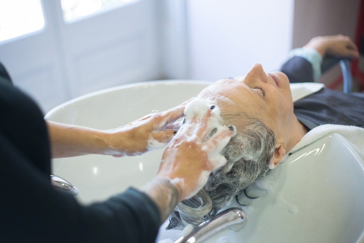 Profissional lavando e massageando o cabelo de uma mulher