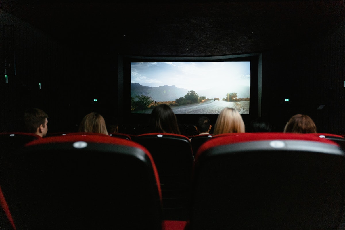 sala de cinema com várias pessoas sentadas  próximas umas das outras