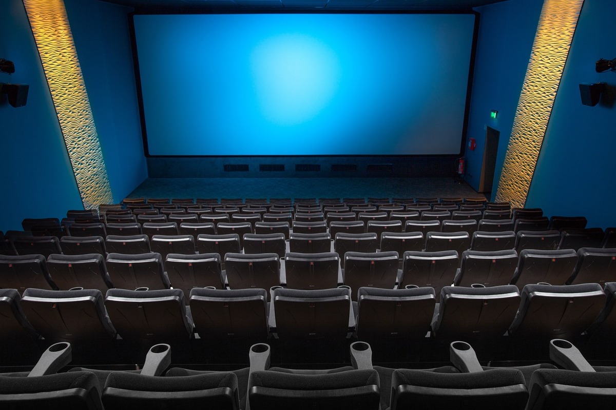 sala de cinema vazia com tela azul e poltronas acinzentadas