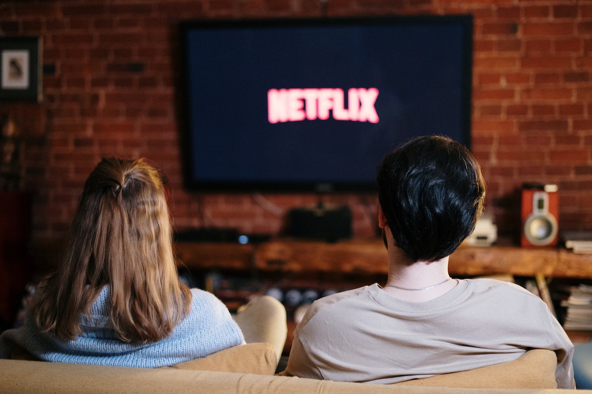 homem e mulher sentados no sofá enquanto assistem Netflix
