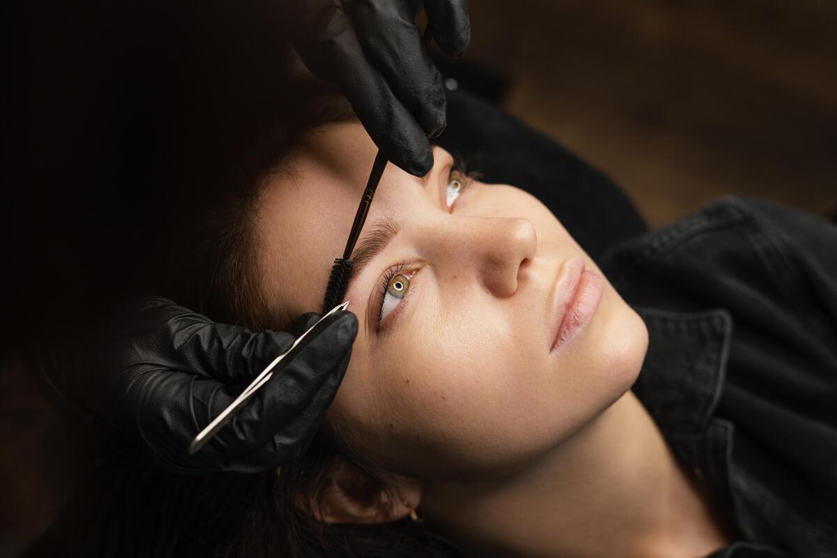 Imagem de uma mulher deitada fazendo micropigmentação nas sobrancelhas
