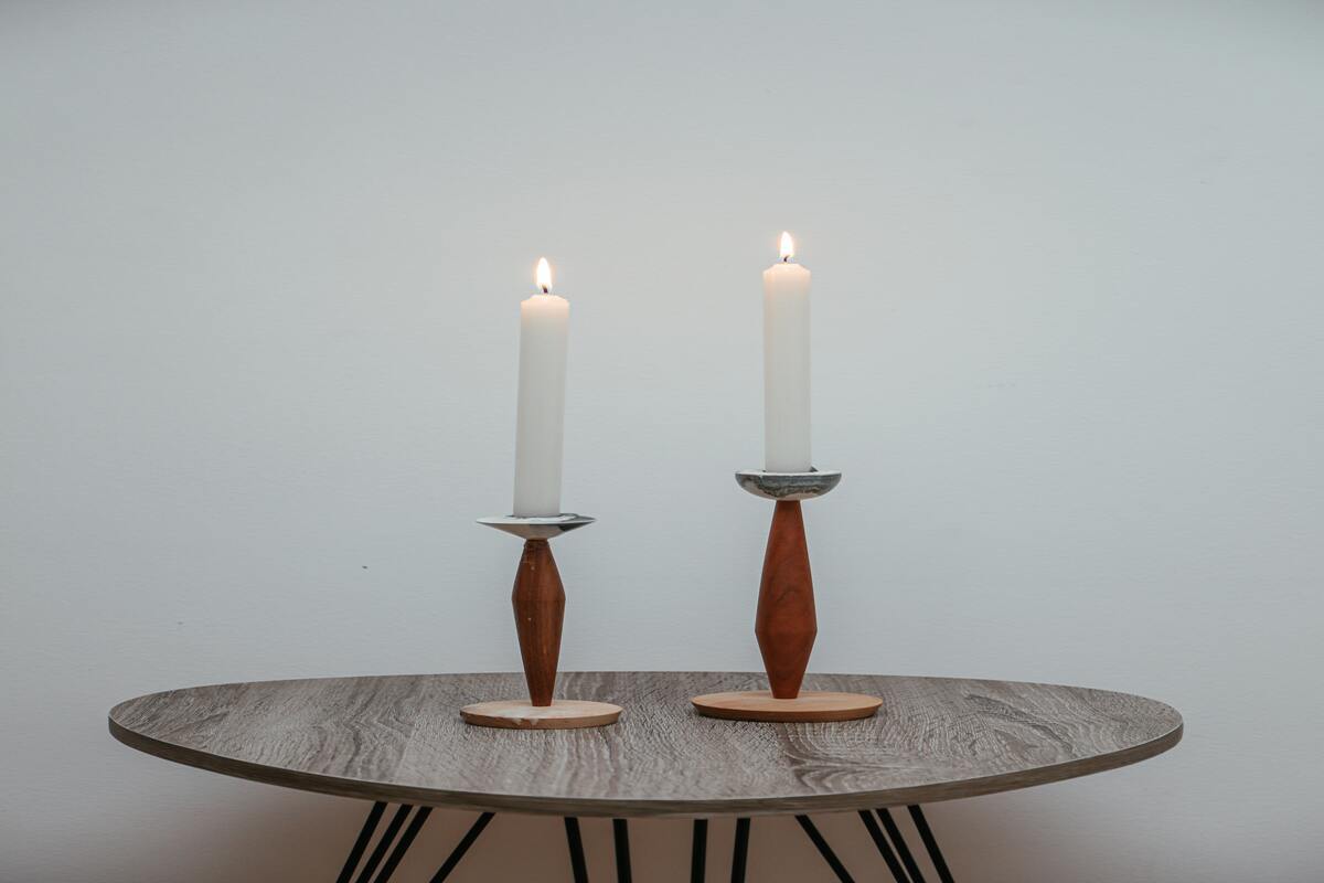 duas velas acesas em castiçais, em cima da mesa. A imagem se refere a um ambiente imersivo para fazer a oração para conseguir emprego