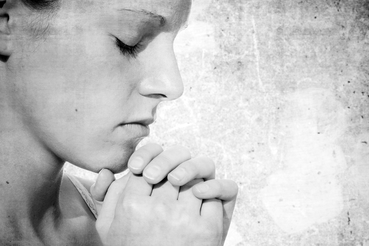 Imagem de uma mulher com os olhos fechados rezando