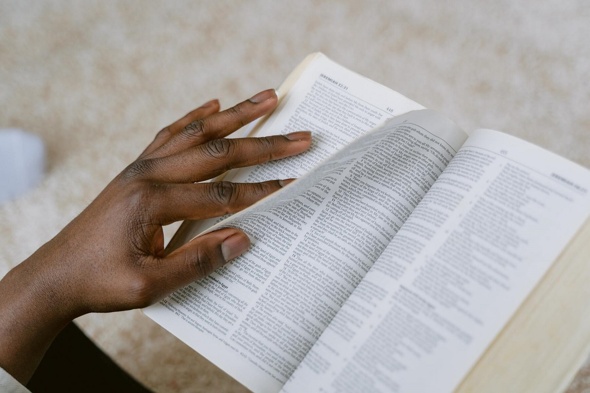 Imagem de uma mão feminina foleando a bíblia sagrada