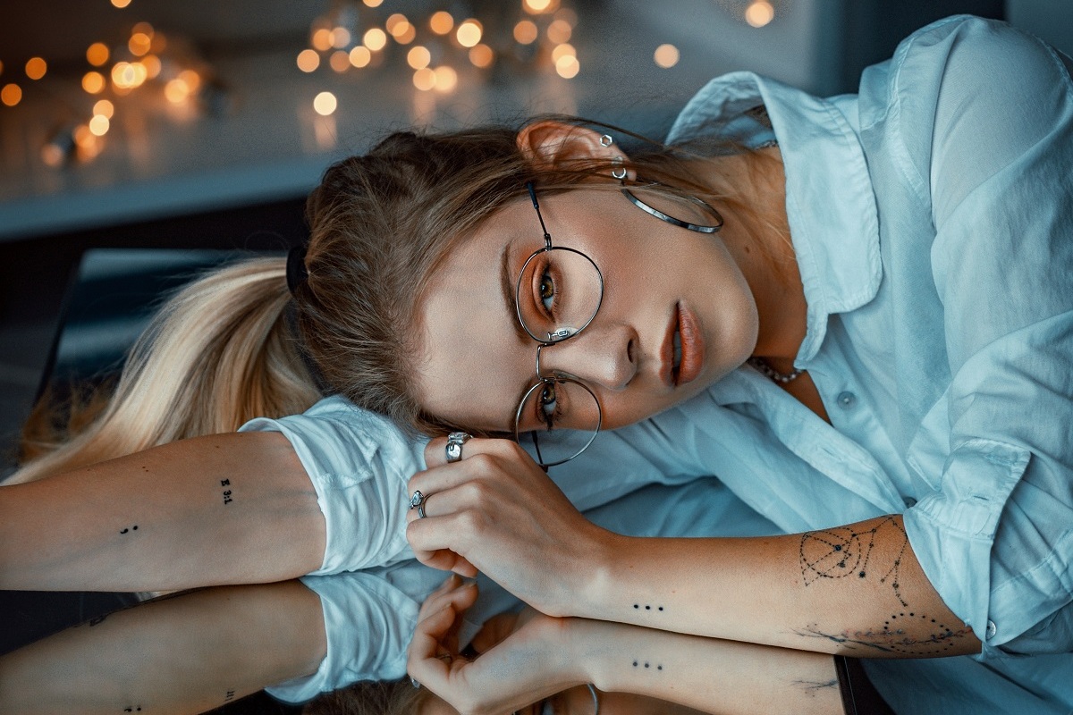 Imagem de uma mulher, com tatuagem, deitada sobre uma mesa