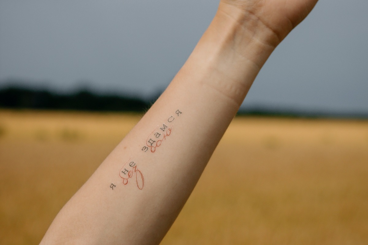Imagem de um braço feminino erguido com uma tatuagem