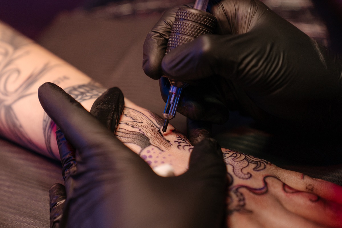 Imagem de um tatuador fazendo uma tatuagem em um braço feminino