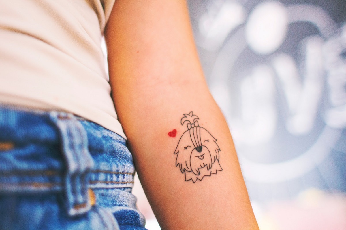 Imagem de um braço feminino com uma tatuagem de cachorrinho