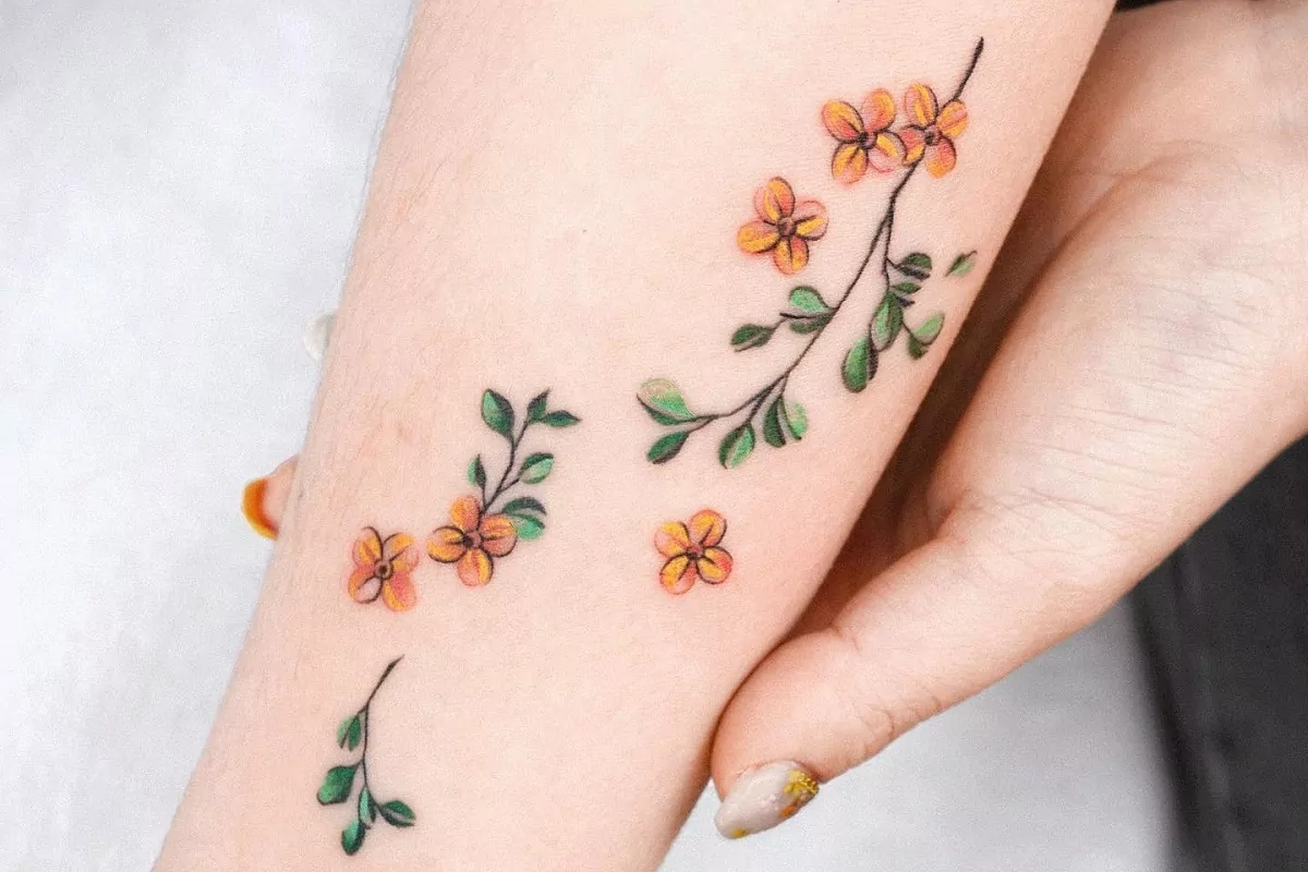 Imagem de um braço feminino com tatuagem floral colorida