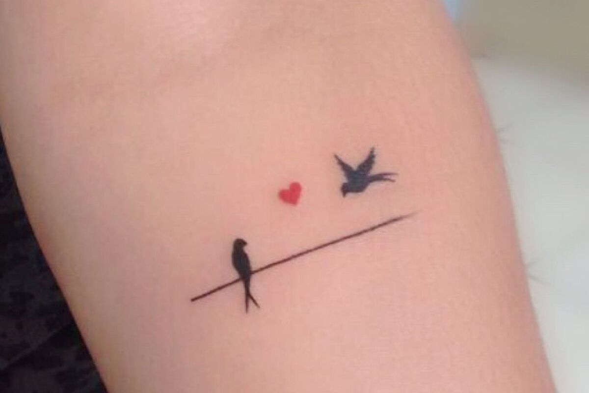 Imagem de um braço feminino com uma tatuagem com pássaros