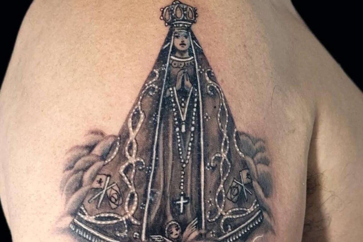 Imagem de um braço masculino com uma tatuagem de Nossa Senhora Aparcida realista