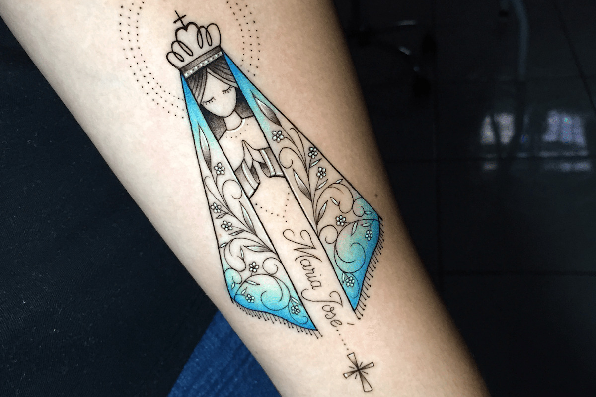 Imagem de um braço feminino com uma tatuagem de Nossa Senhora Aparecida