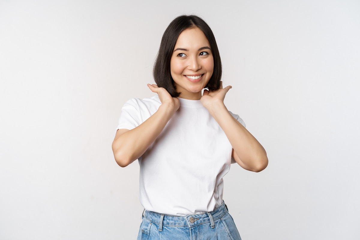 mulher asiática de camisa branca sorrindo de cabelo curto escuro