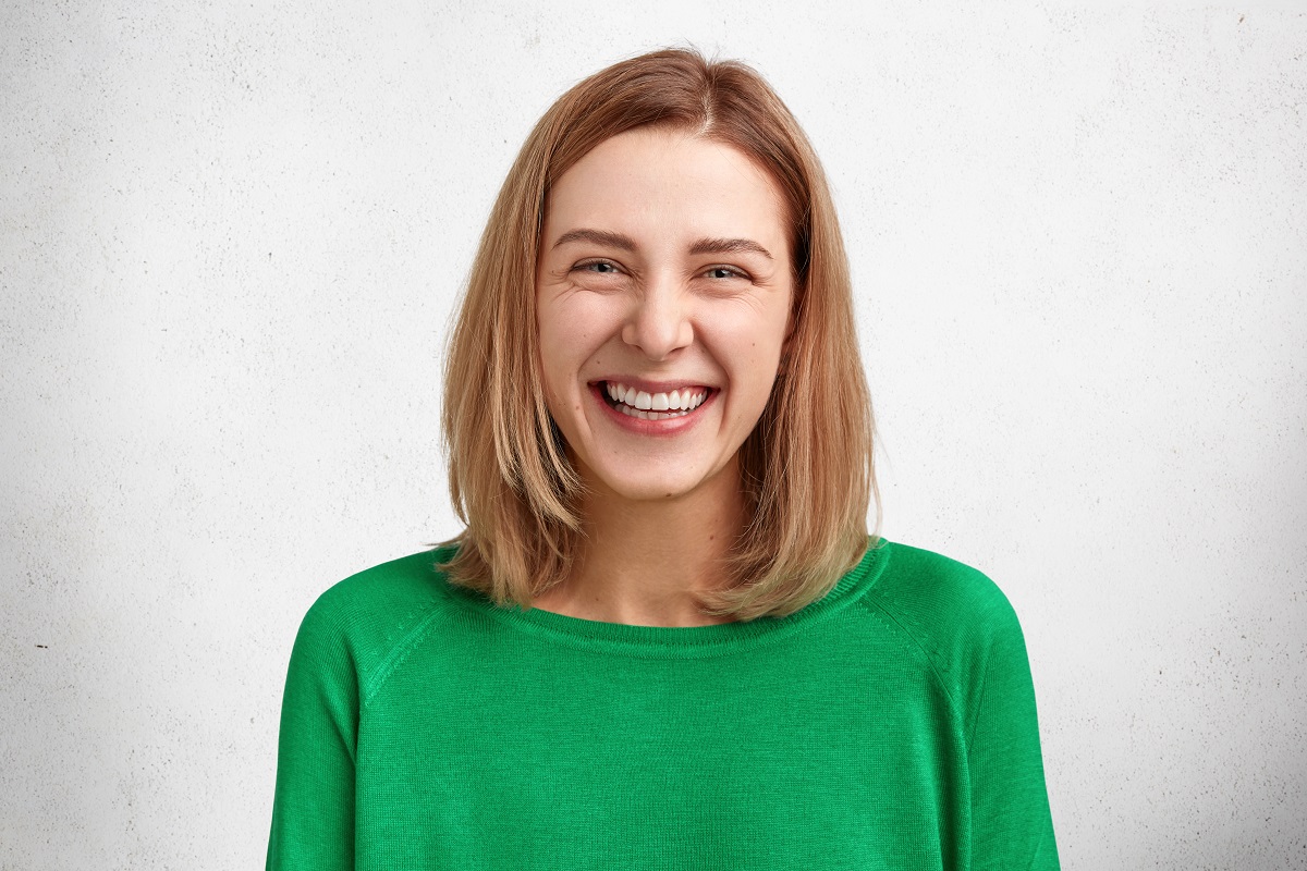 mulher de cabelo curto sorrindo com uma blusa verde