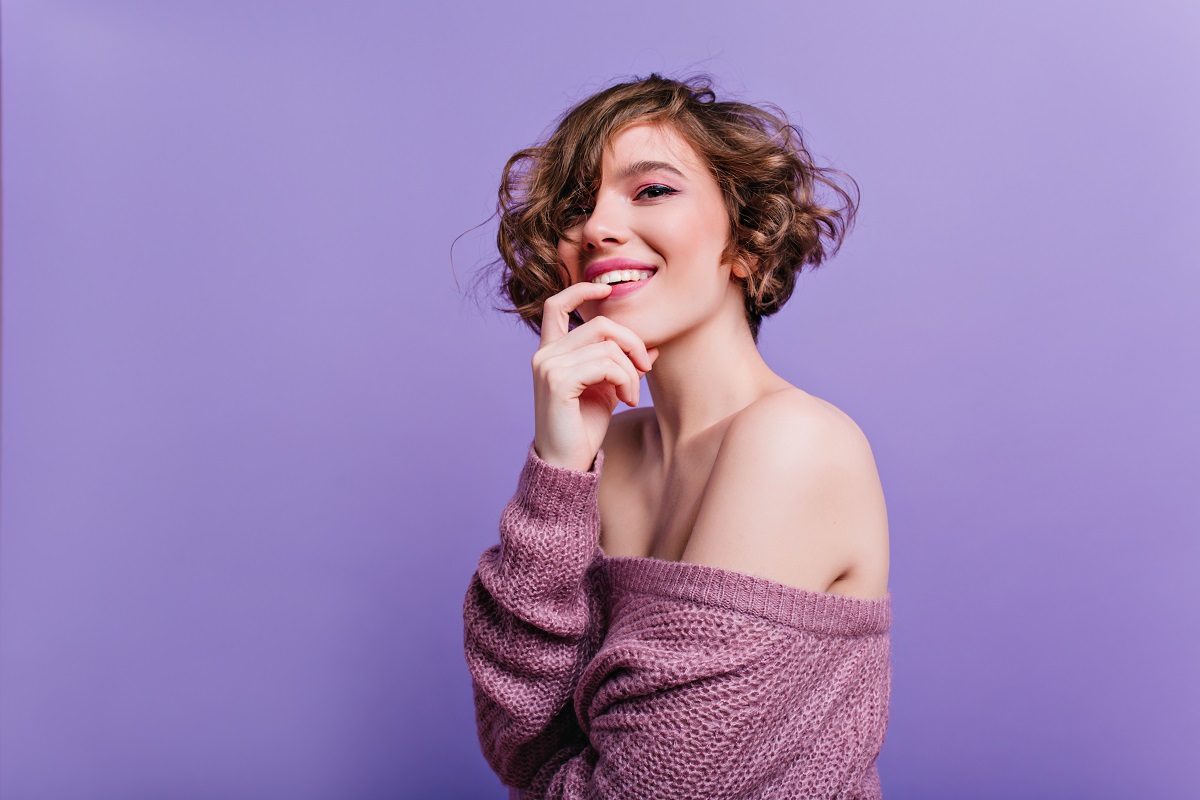 mulher sorrindo de cabelo curto em um fundo lilás