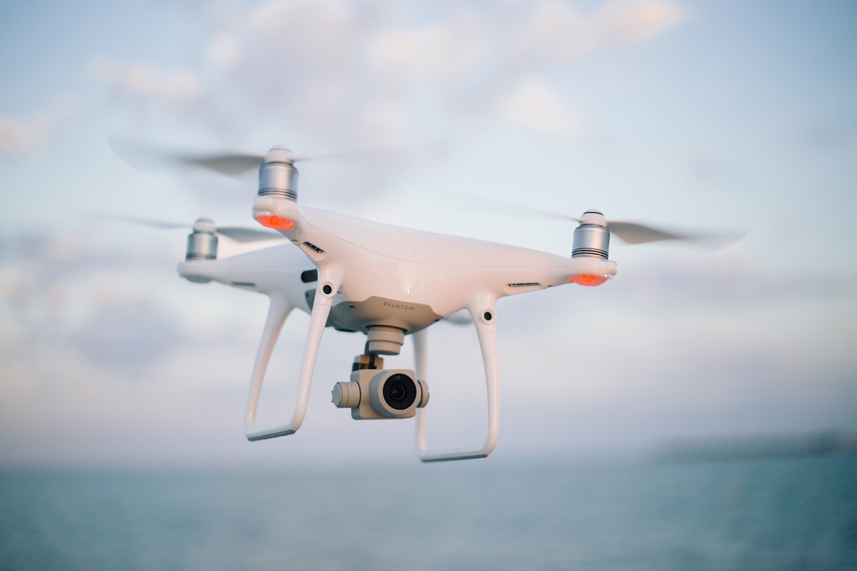 drone branco voando, com uma câmera embaixo dele