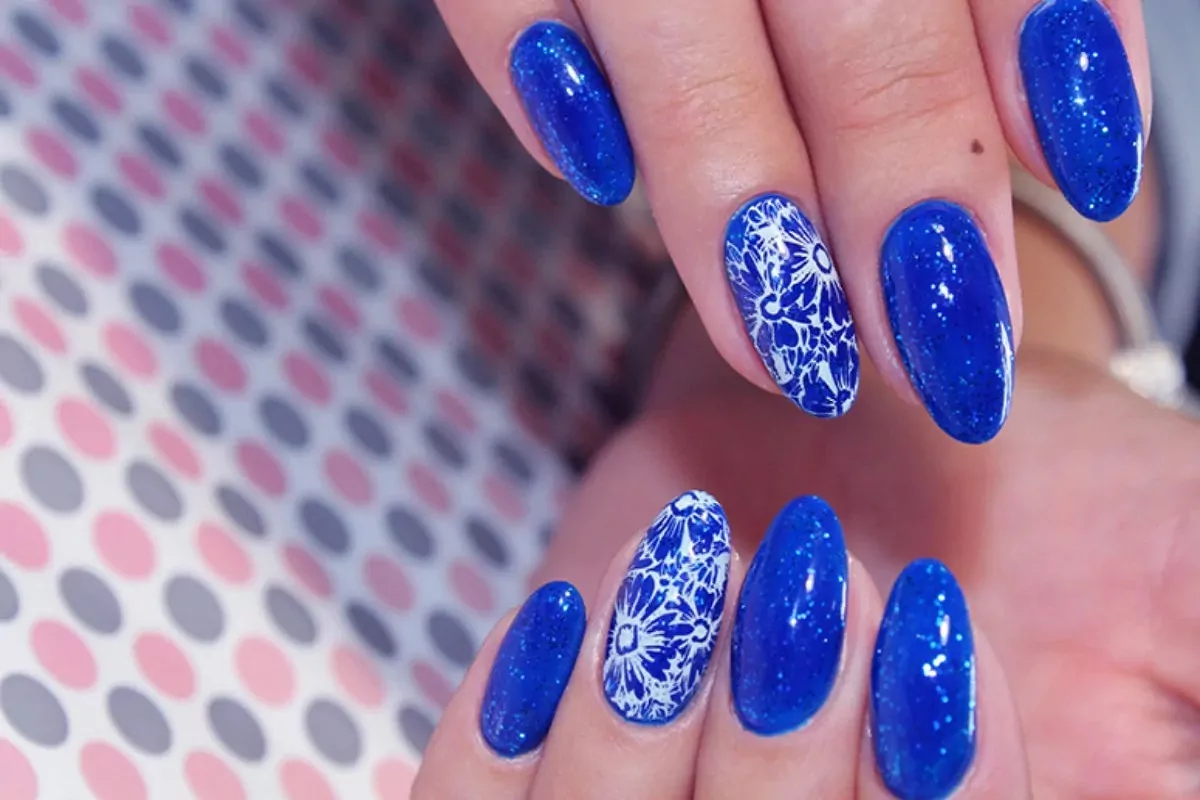 Mãos femininas sobre pano com bolinhas coloridas e unhas em azul