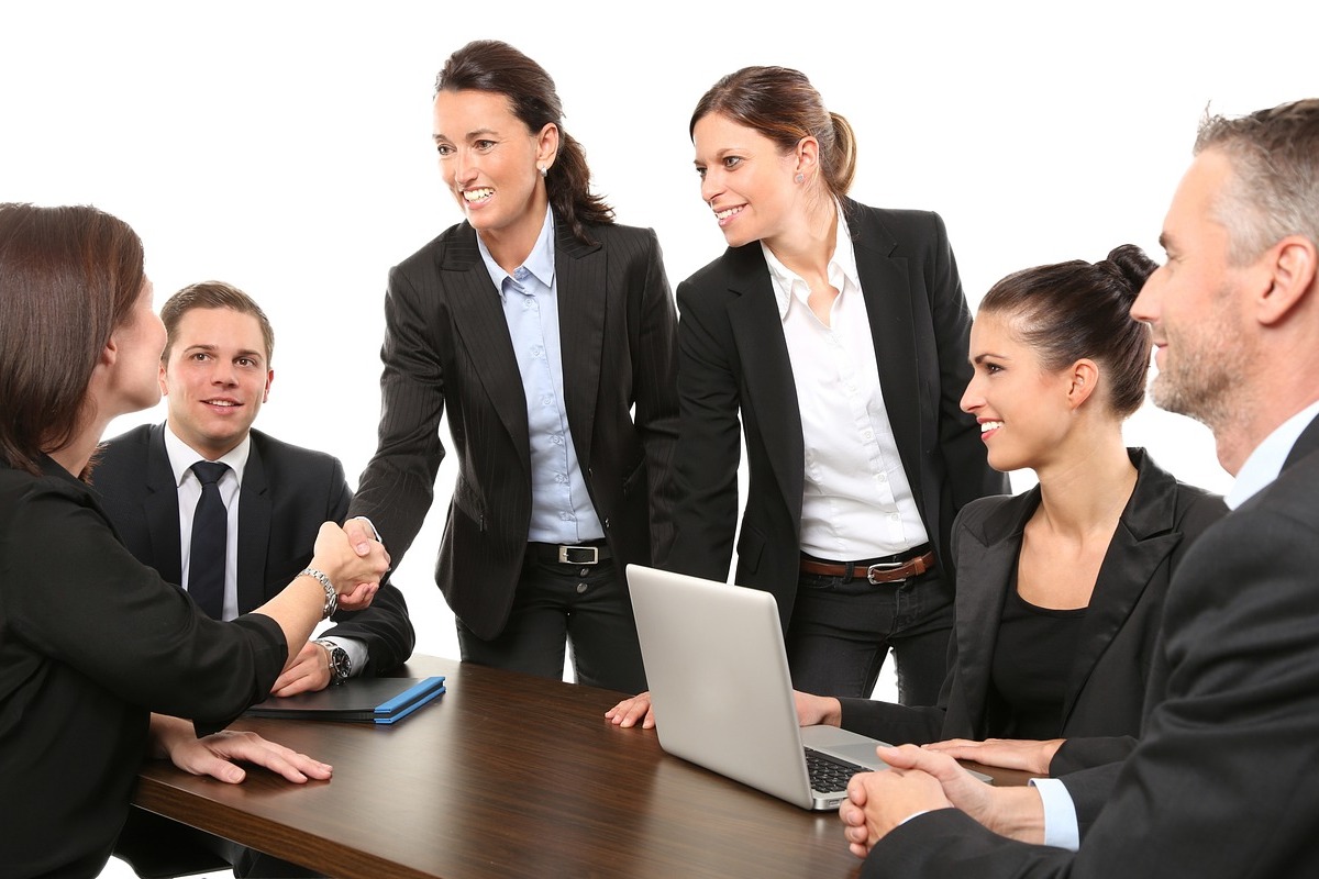 Mulheres: A imagem mostra três mulheres de terno e uma reunião de trabalho com dois homens. 