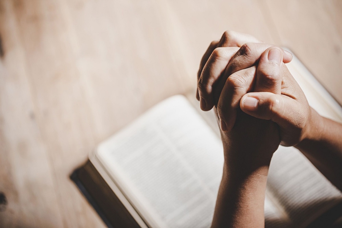 Oração e jejum: A imagem mostra uma pessoa orando sobre uma Bíblia