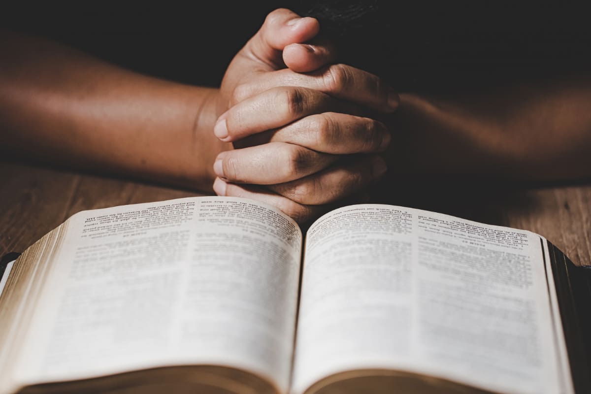 Salmos 66: A imagem mostra uma pessoa orando perto de uma Bíblia