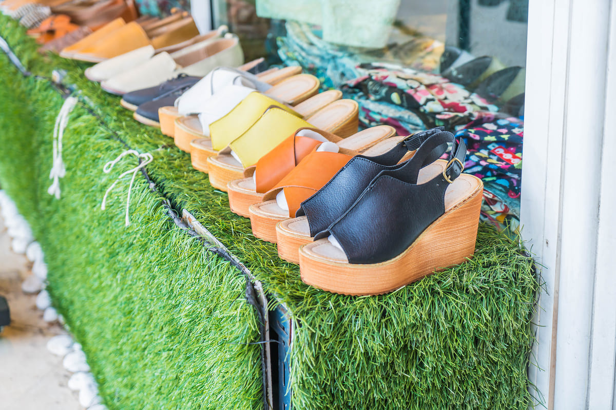 Sapatos femininos: A imagem mostra diversos sapatos plataformas sobre uma mesa e com tapete estilo gramado. 