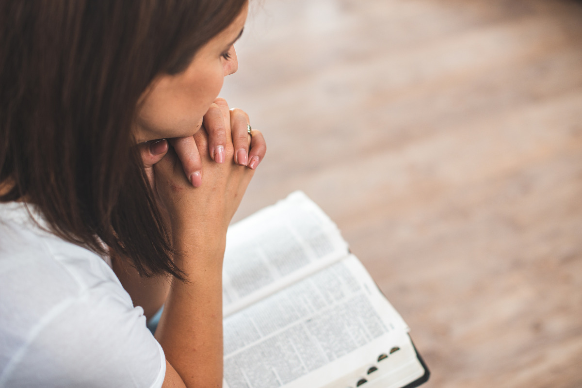 Mulher rezando de olhos fechados as orações do Cerco de Jericó
