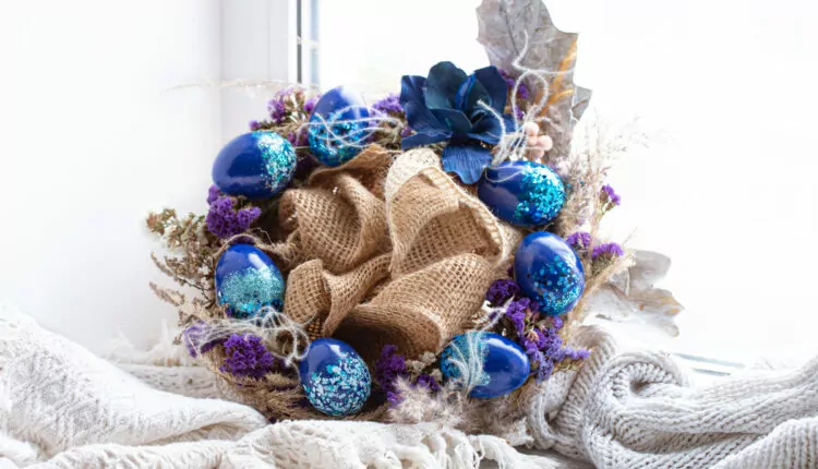 guirlanda de páscoa adornada com ovos azuis, flores e galhos secos