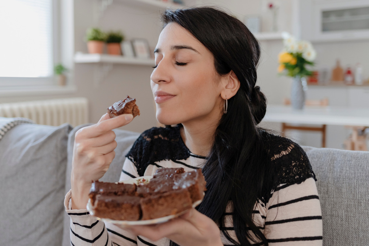 Legenda para foto de bolo nas redes sociais; na foto, mulher saboreando uma fatia de bolo