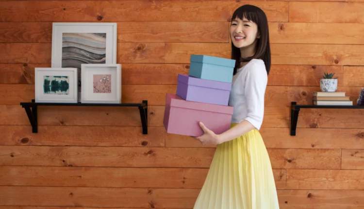 Marie Kondo segurando caixas de arrumação